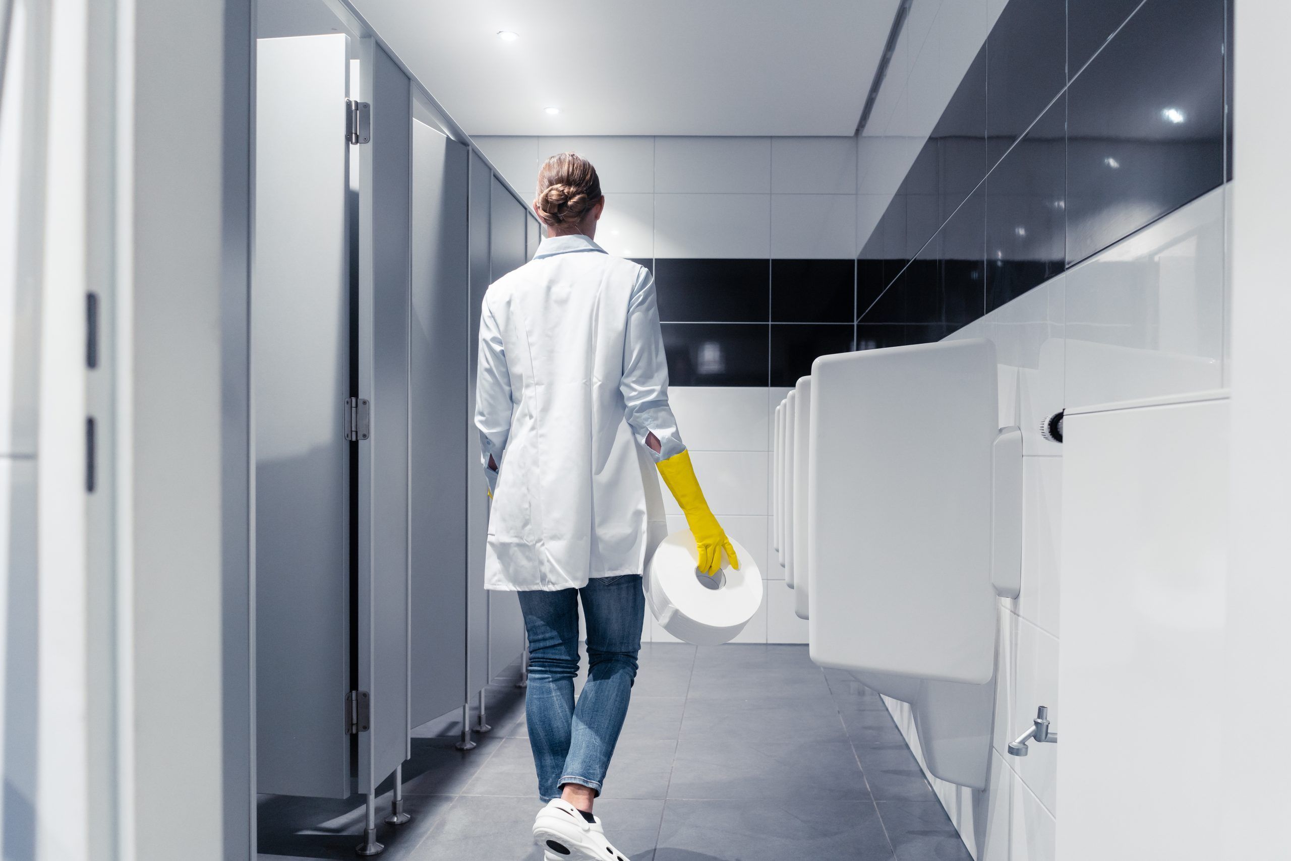 Janitor woman changing paper in public toilet or restroom